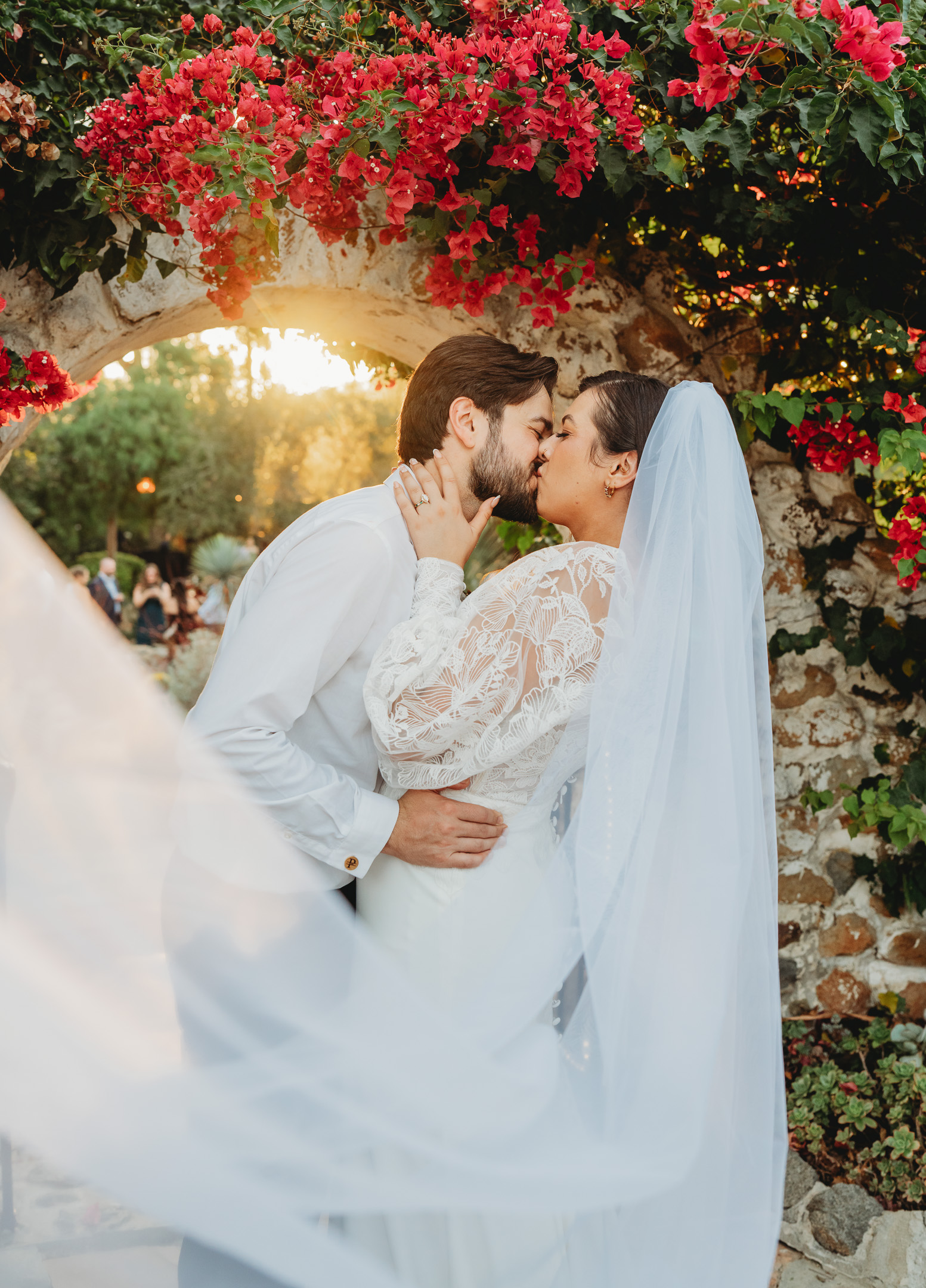 Bride and groom kissing under a flowering archway